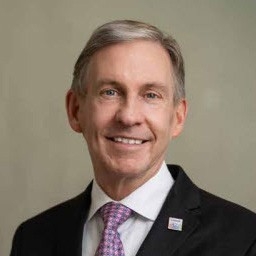 Man in black suit with pink and purple tie.