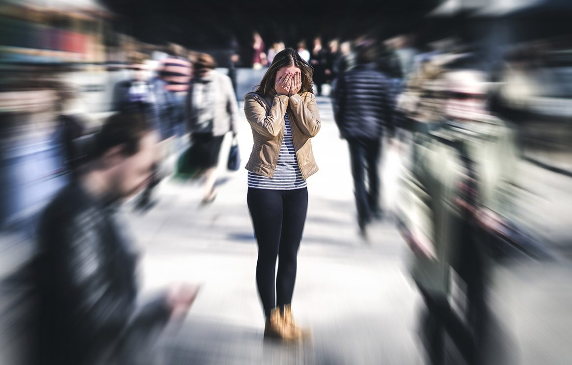 Dark-haired woman with face covered in clear focus as blurry crowd rushes around her
