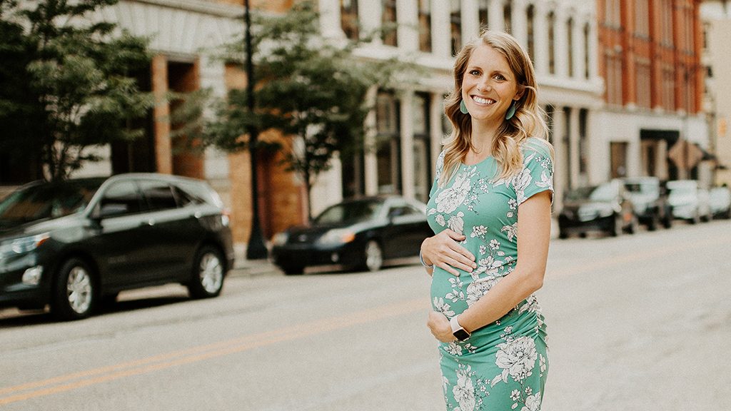 Stomach cancer survivor Emily Aldrich touches her pregnant stomach
