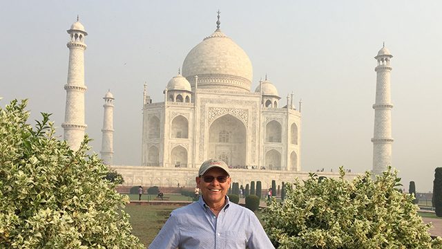 Multiple myeloma survivor Steven Champagne stands in front of the Taj Mahal in Oct. 2018. He is smiling and wearing a baseball cap and sunglasses.