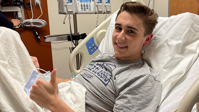 20-year-old colorectal cancer survivor Jaystan Davis, smiling and giving the "thumbs-up" sign from his hospital bed