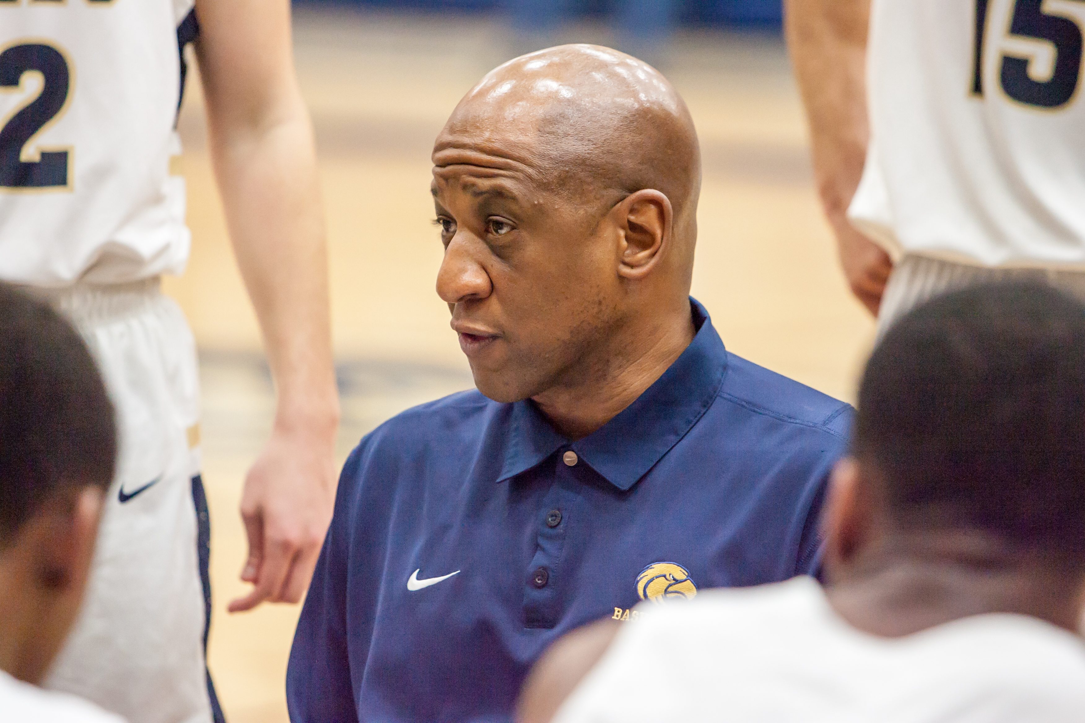 Kevin Mouton stands in a huddle surrounded by his high school basketball team at a game in Feb. 2018.