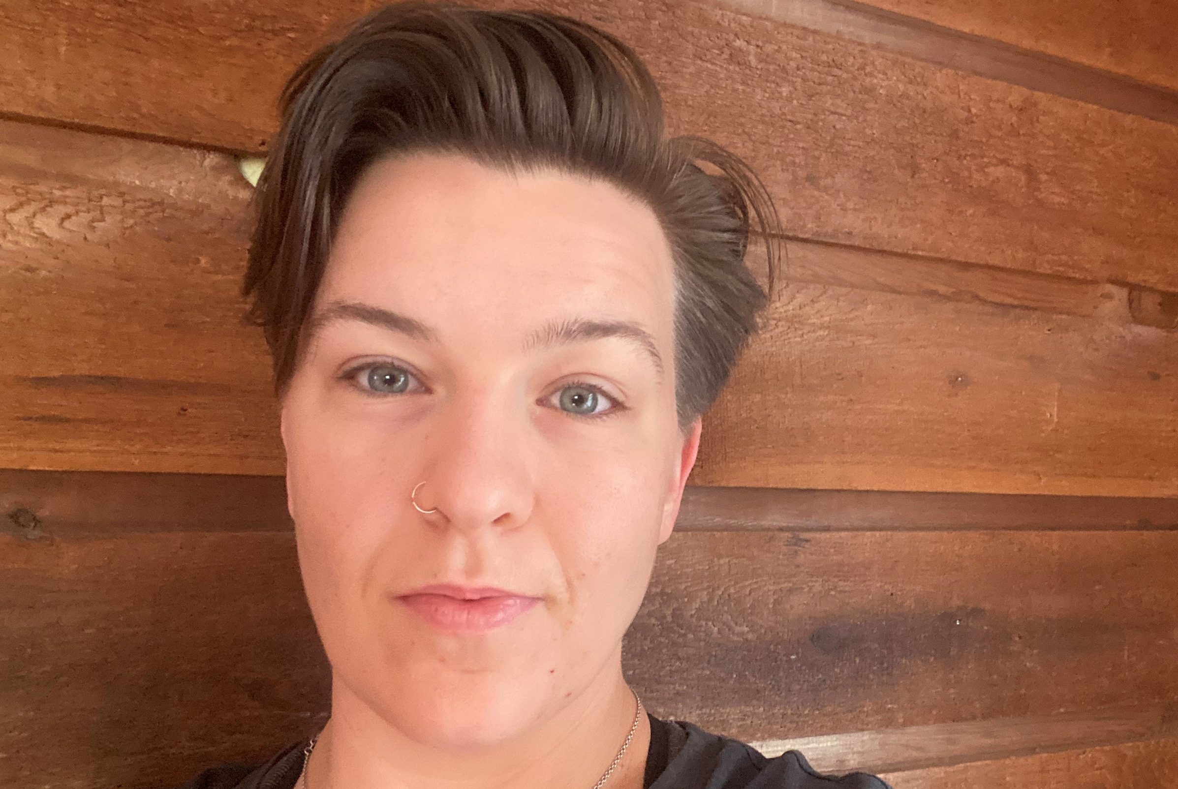 Selfie of Katherine Norman taken against a wood paneled wall