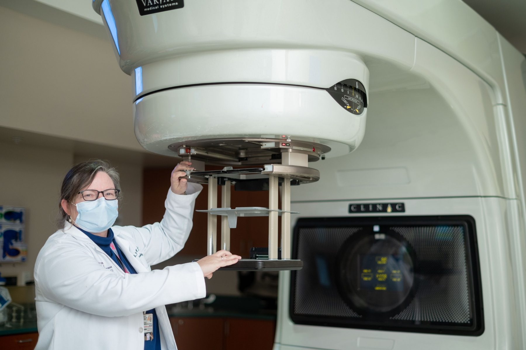 Wendy Woodward, M.D., Ph.D., stands next to a radiation therapy machine.