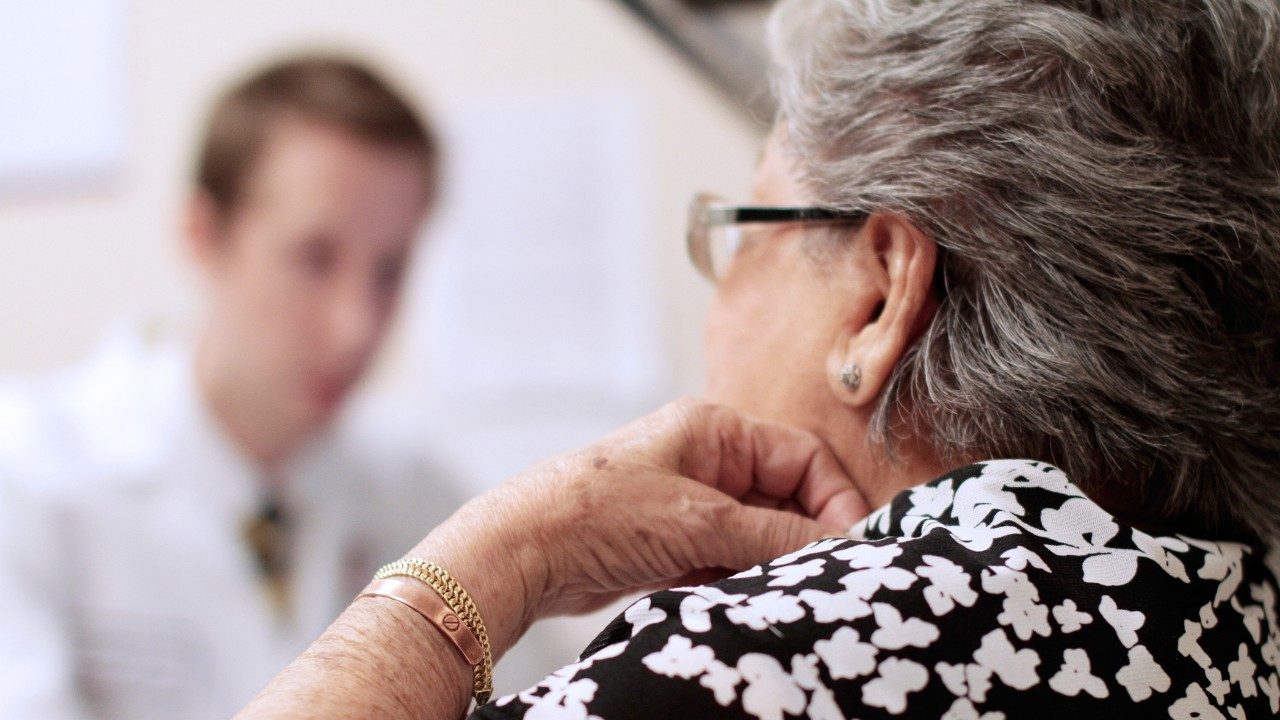 Older cancer patient speaks with doctor about clinical trial options.
