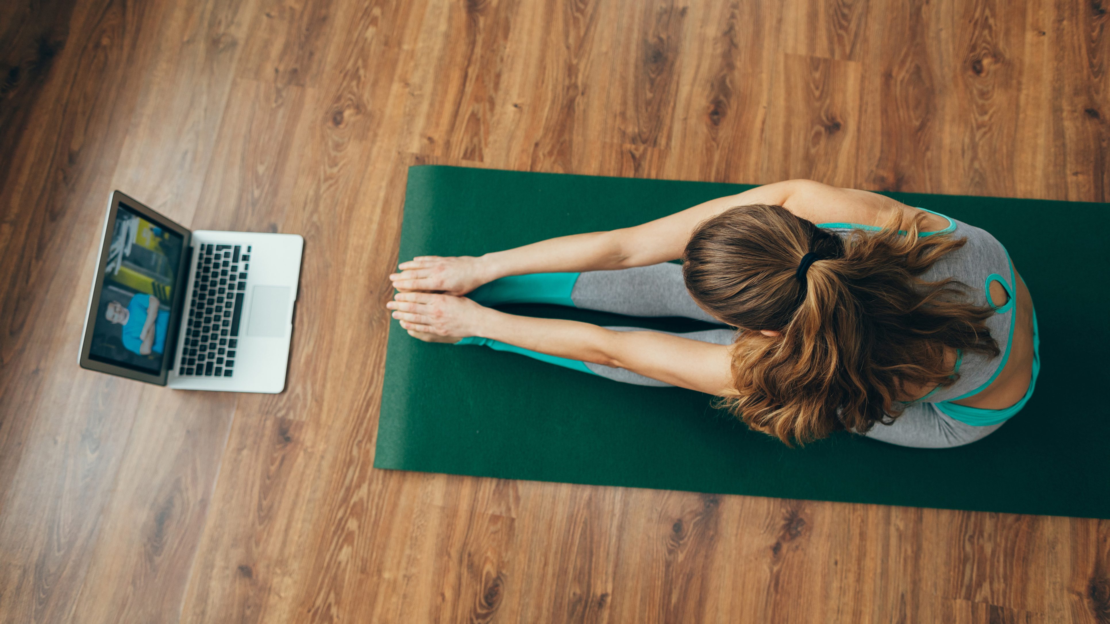 Woman doing yoga at home while looking at computer screen