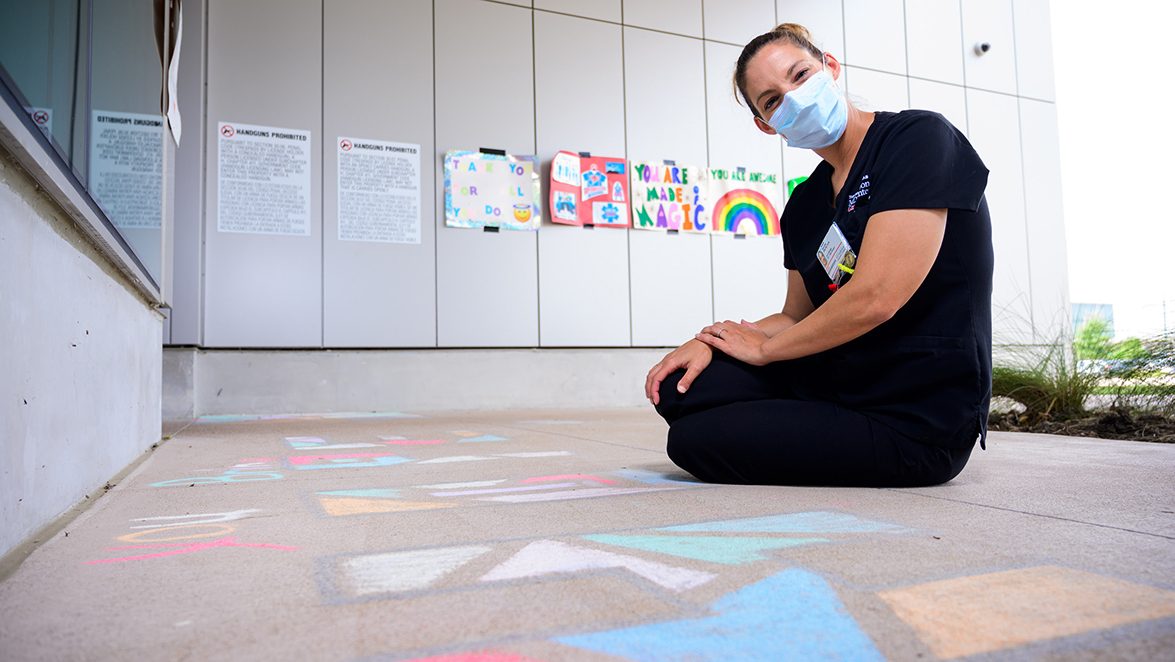MD Anderson West Houston nurse manager Natalie Sanchez sits on the ground beside chalk art she and her team created for cancer patients