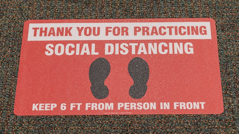 Red sticker with social distancing reminder on the floor at MD Anderson