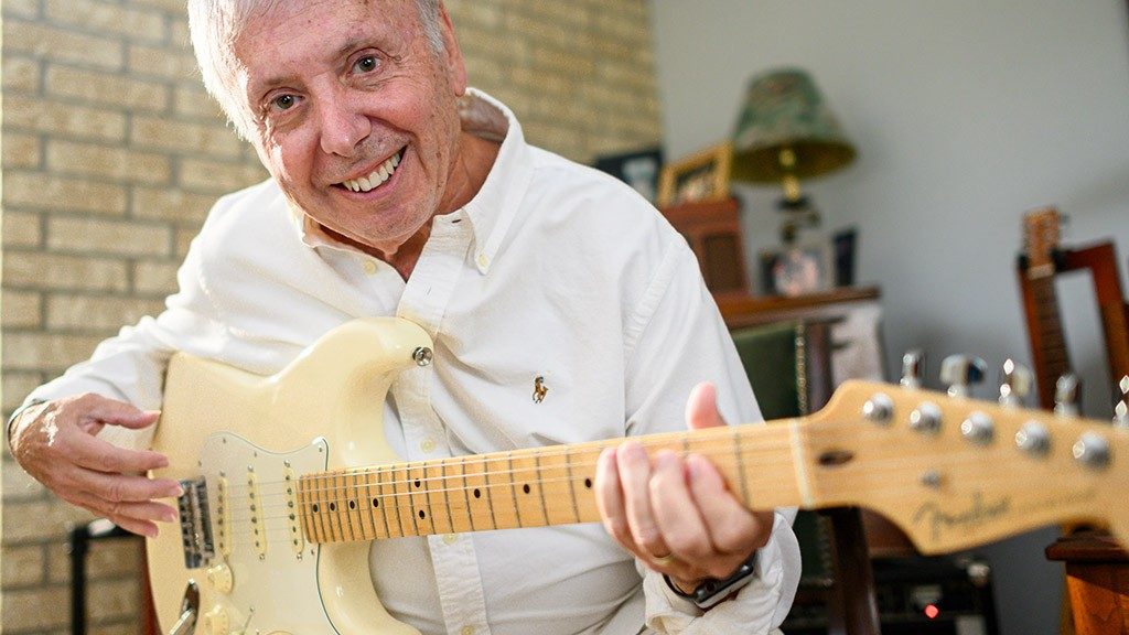 Stage IV melanoma survivor Mark Zindler holds his guitar