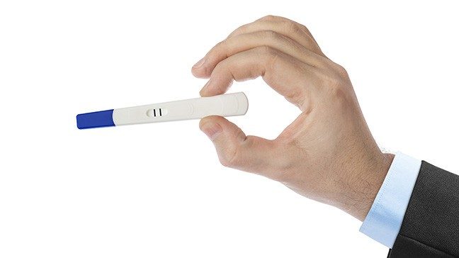 Man's hand holding a positive pregnancy test