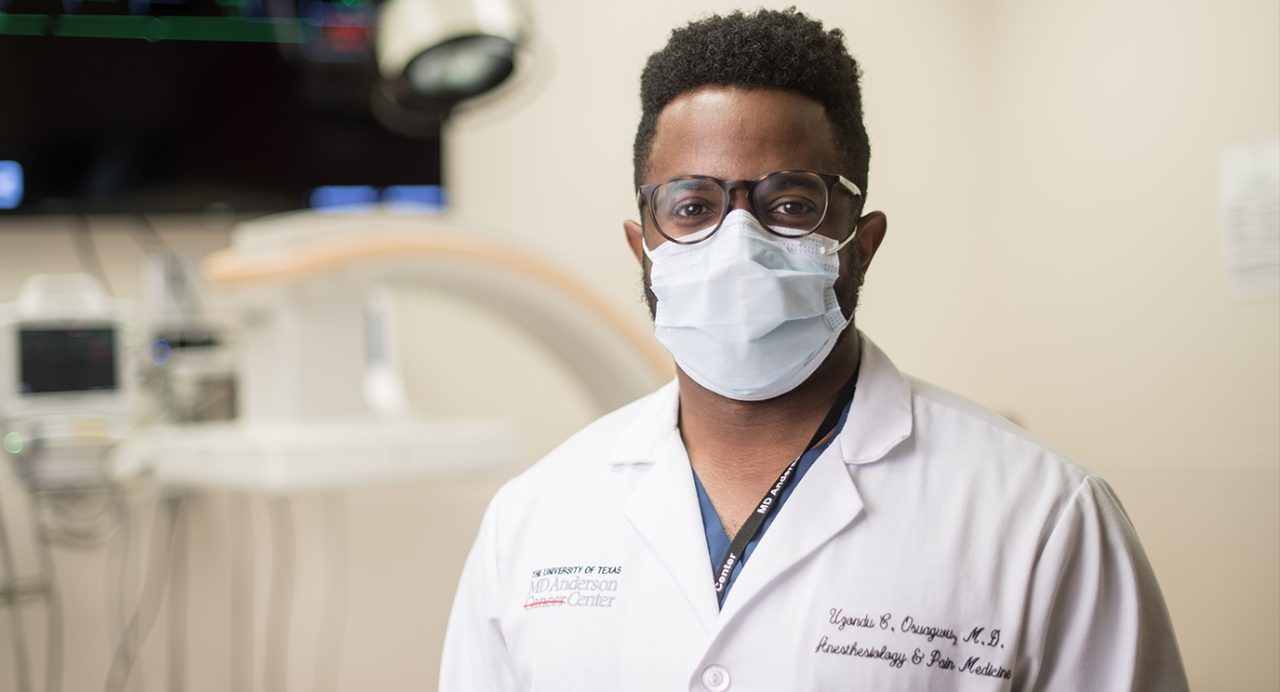 Pain management specialist Uzondu Osuagwu, M.D., in his white coat and medical-grade face mask