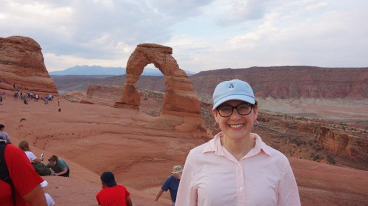 Breast cancer and leukemia survivor Julie Hildebrand, M.D., wears a hat and smiles in Arches National Park