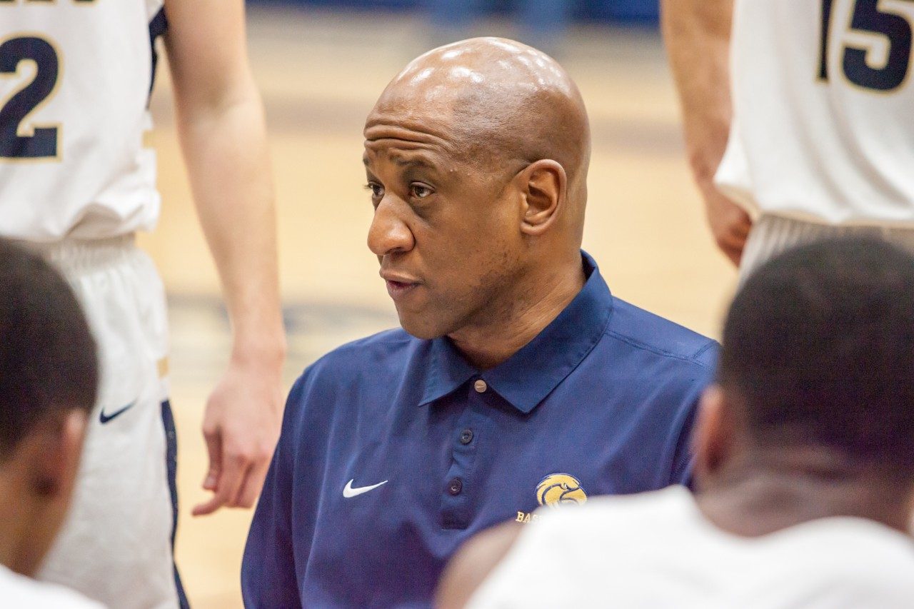 Kevin Mouton stands in a huddle surrounded by his high school basketball team at a game in Feb. 2018.