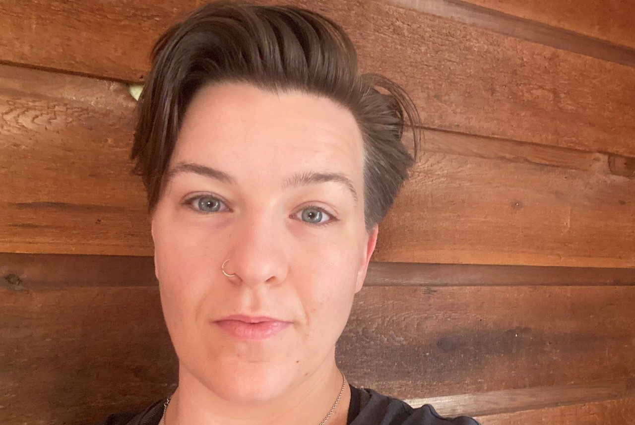Selfie of Katherine Norman taken against a wood paneled wall