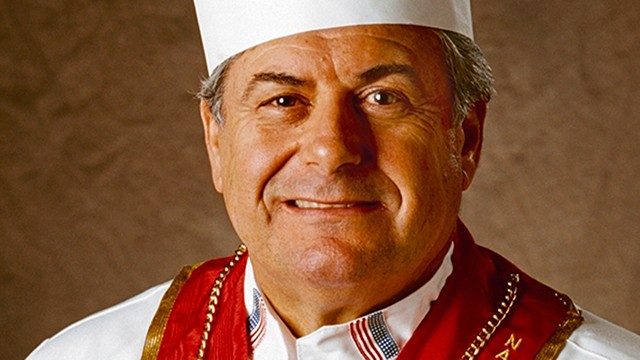 Mucosal melanoma survivor Bert Cutino, wearing a chef's hat, smiles at the camera.