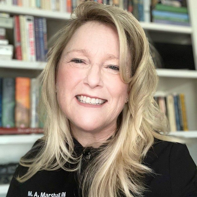 Mary Anne Marshall in an office with shelves of books behind her.