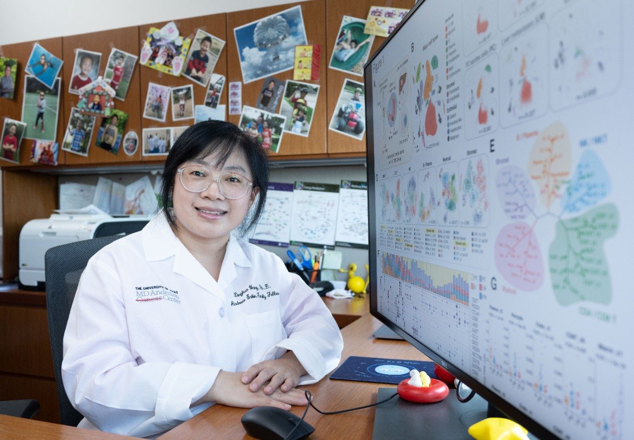 Dr. Linghua Wang sits at a desk in front of her computer