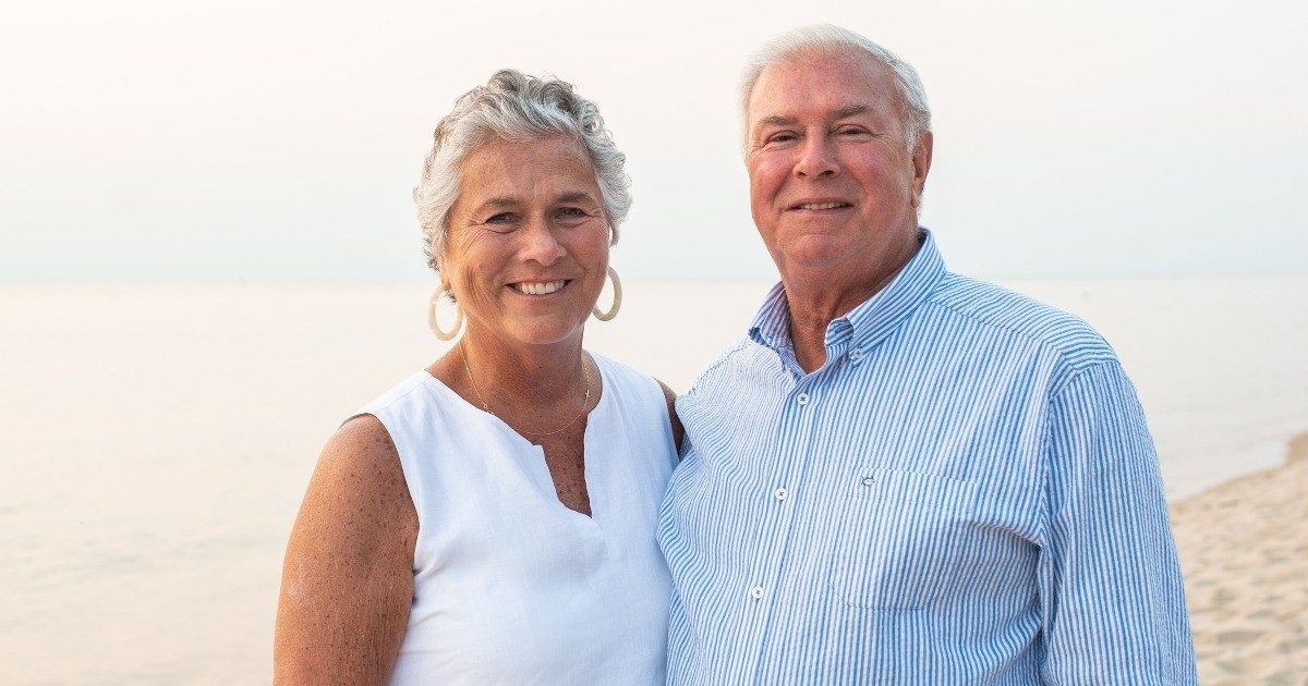 Adrienne and Bill DeNooyer standing on a beach.