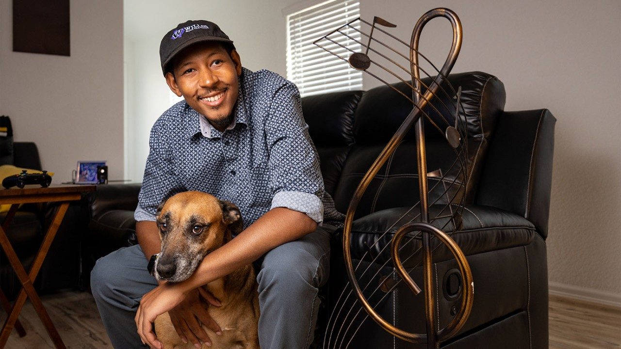 Germ cell tumor survivor Eric Roberson Jr. hugs his dog, Madame, with a music note to his right