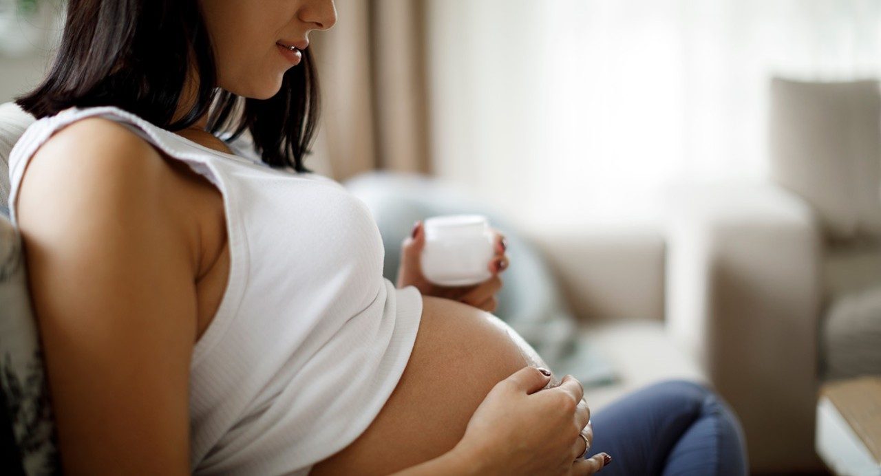 Pregnant person looking at her belly. 