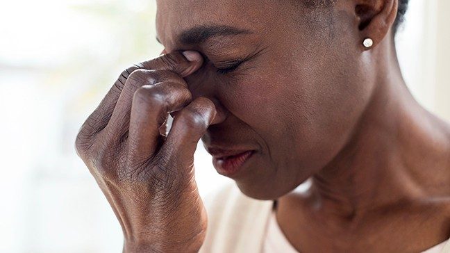 Woman is holding her nose in pain