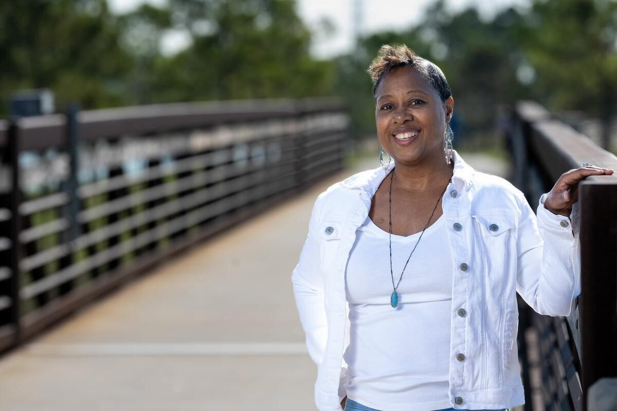 Jewel stands outside wearing a white shirt and jacket