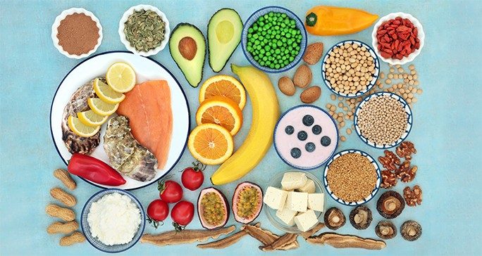 Bird's eye view of fresh foods that are good sources of Vitamin B against a turquoise background