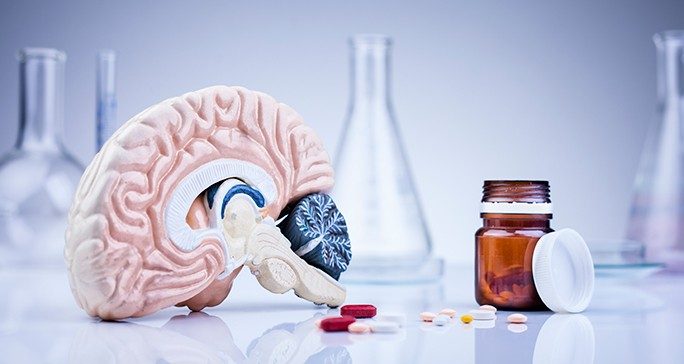 Graphic of a brain next to a pill bottle with pills scattered