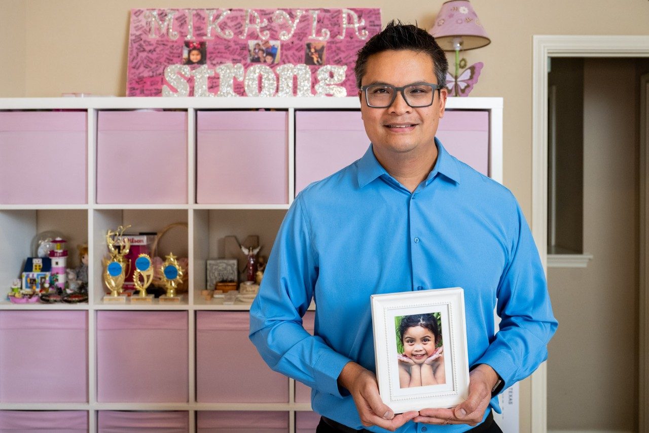 Rodney Quindoy holds a photo of his late daughter, Mikayla, in her bedroom surrounded by her things.