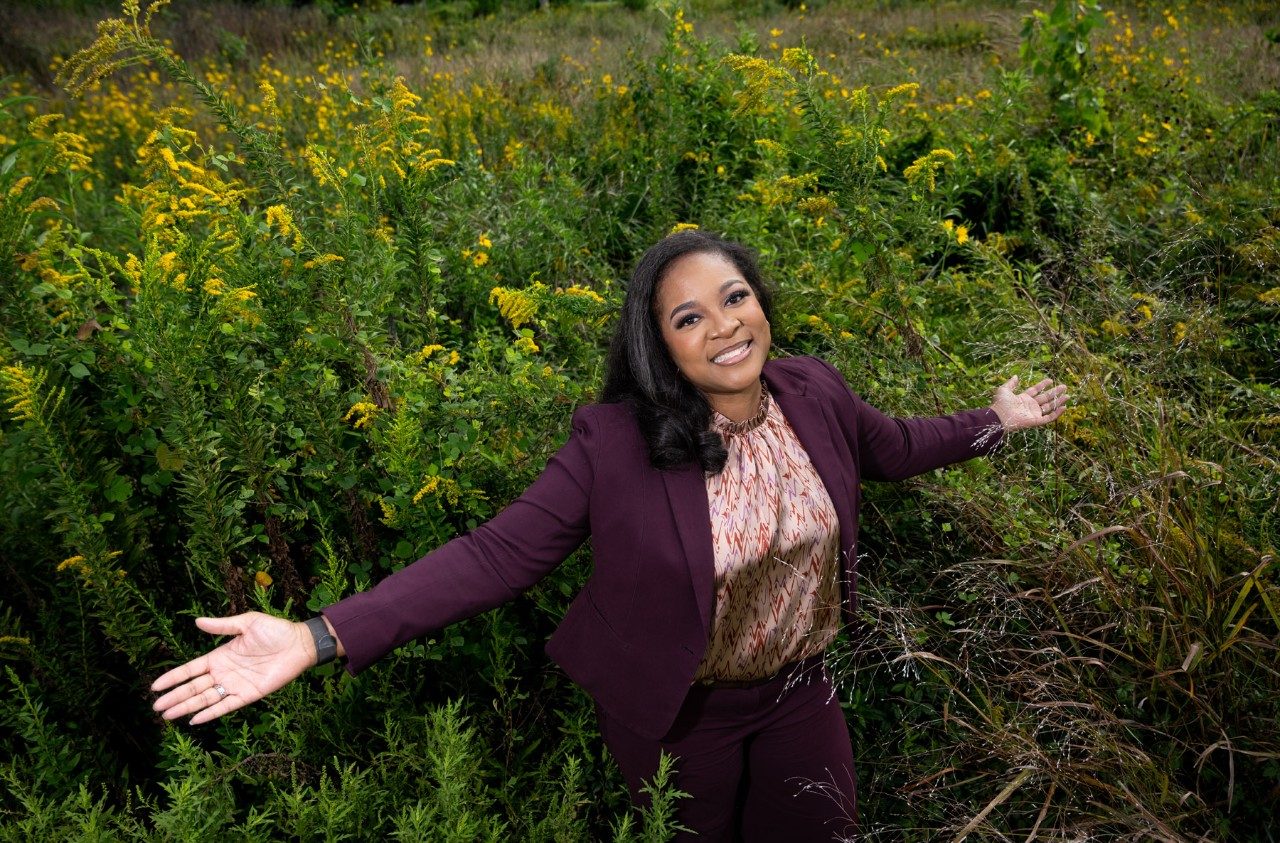 Linette Leadon poses in a field with her arms outstretched