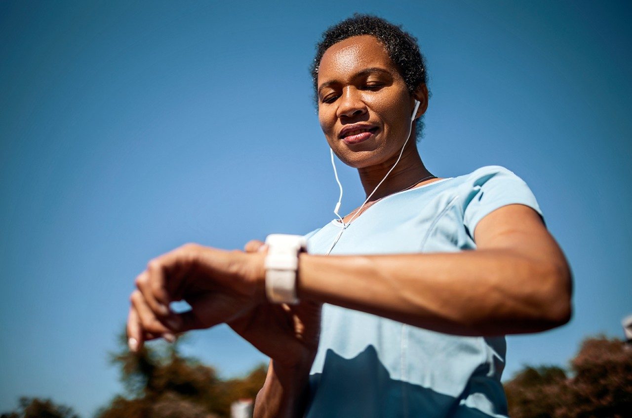 A black woman looks at the heart rate monitor on her watch