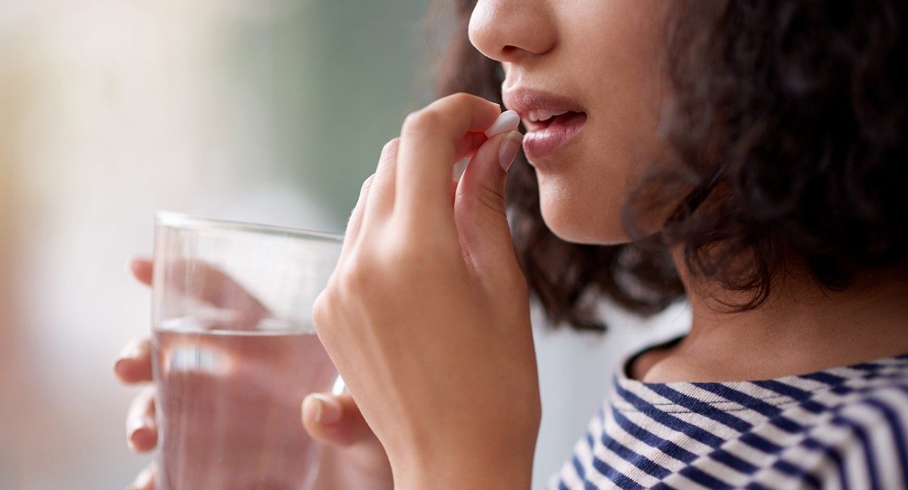 Close-up of unidentifiable young woman taking a pill 