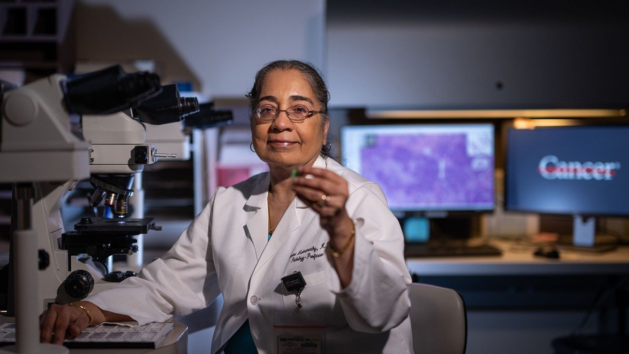 Savitri Krishnamurthy, M.D., holds up a pathology slide in her lab.