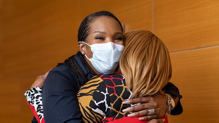 Fayleta Lawerence, masked, hugs patient.