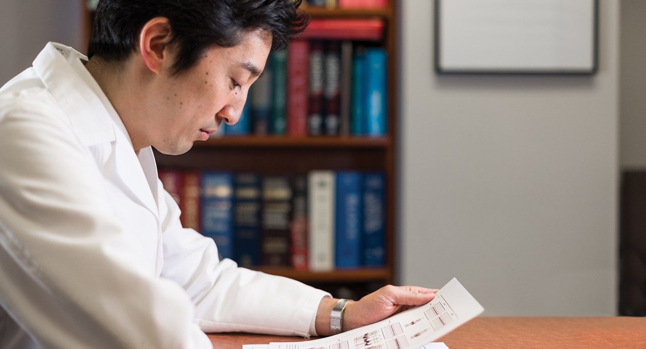 Koichi Takahashi, M.D., reading a medical report