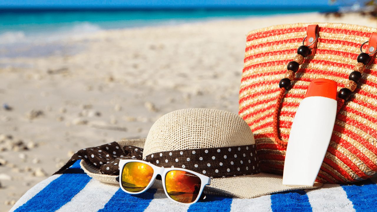 hat, sunglasses and beach bag on a towel on the beach