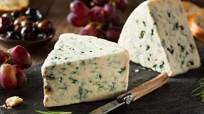 Two blocks of blue cheese on a chopping board