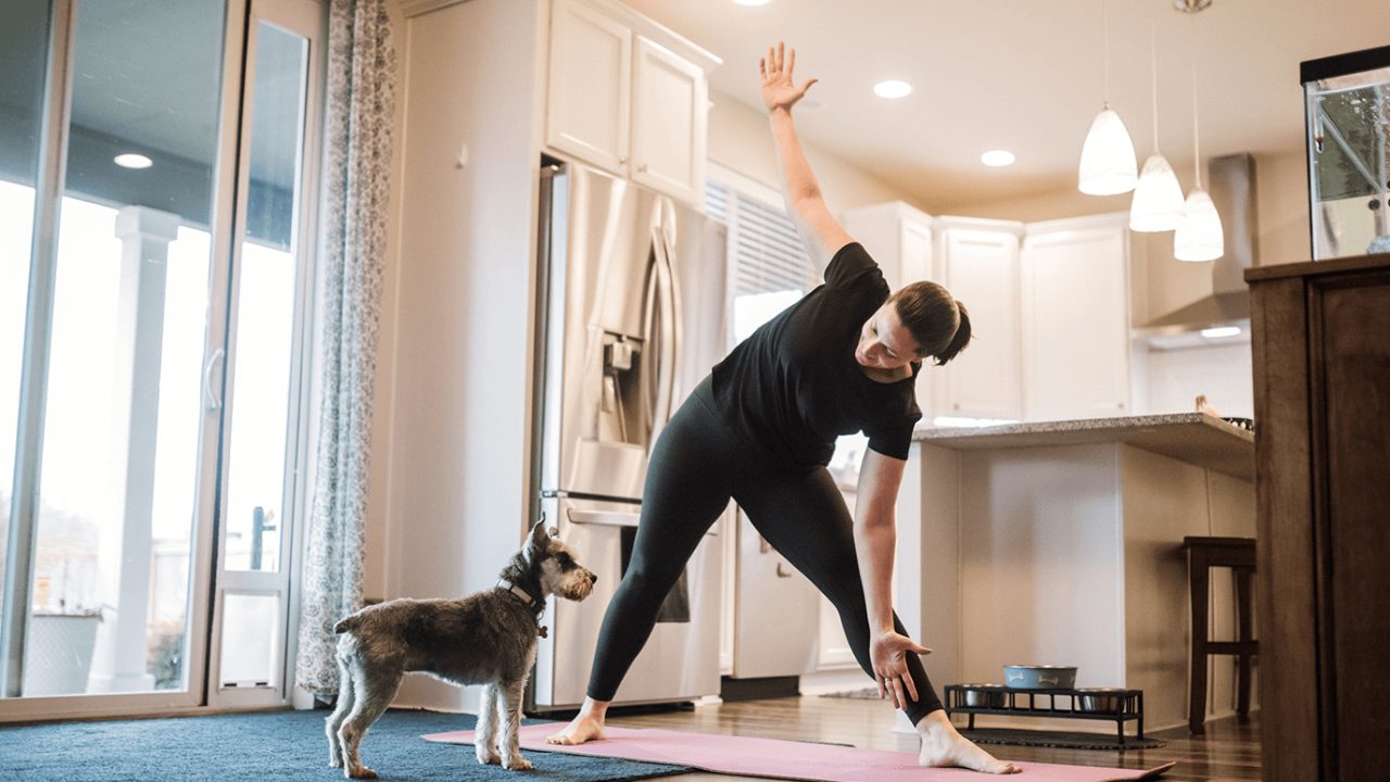 woman stretching at home with dog
