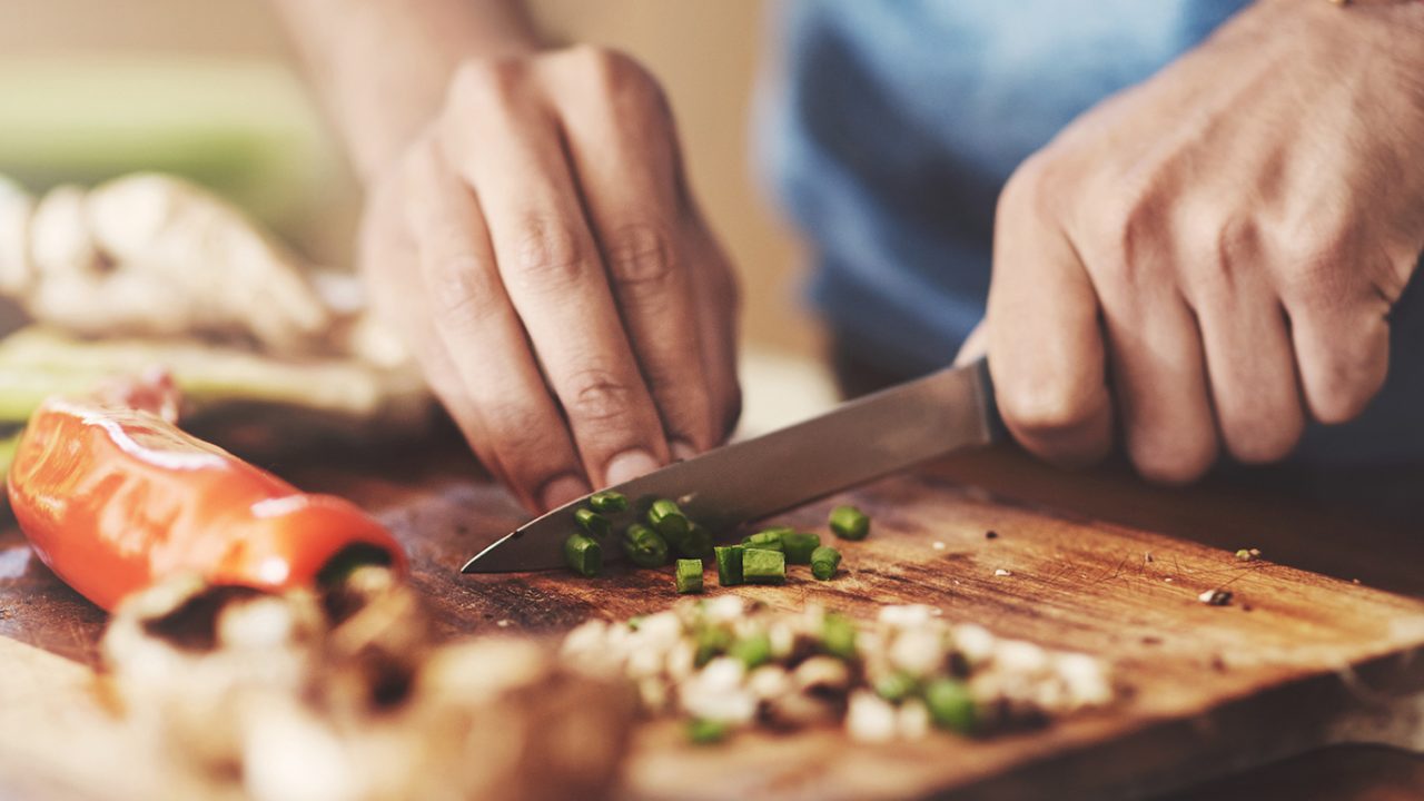 Person chops green onions on board