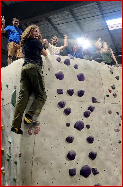 Group of people at the top of a rock climbing wall as one person finished their ascent