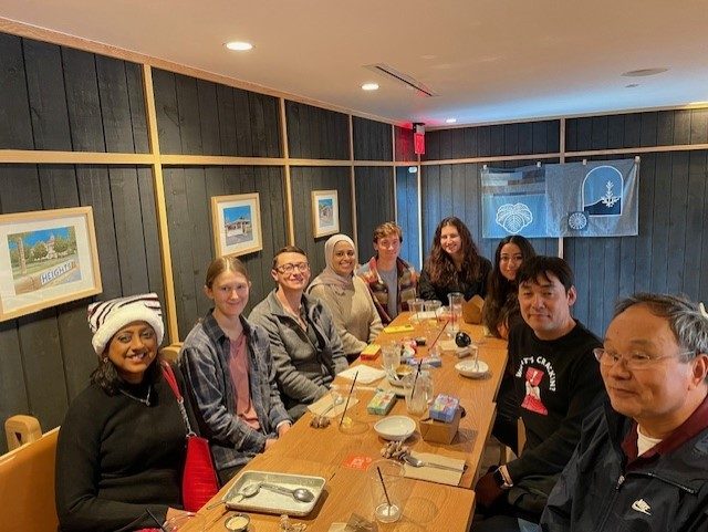 Students and PI gathered around table posing for picture at lunch