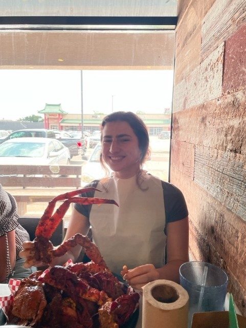 Labstudent posing with boiled seafood at a lunch with fellow lab members.