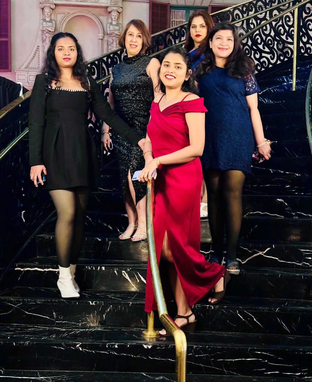 Five lab members in formal wear pose on a staircase