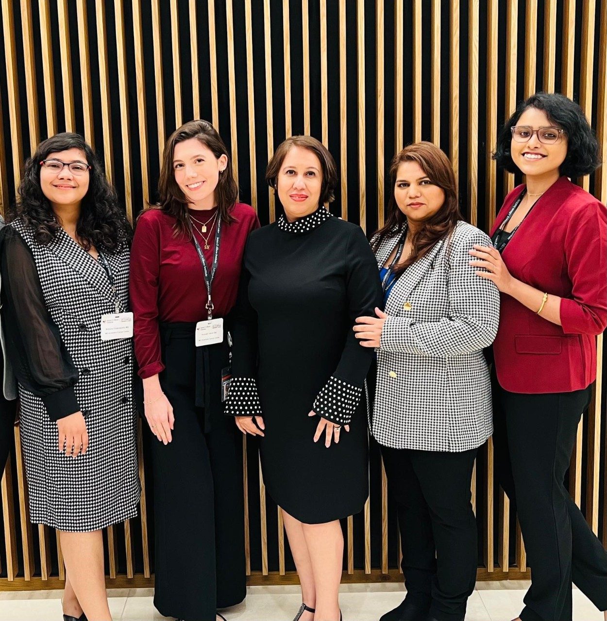 Five lab members pose in a line, all wearing black, white, and red