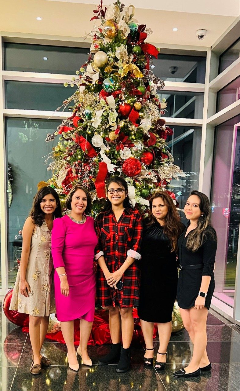 Five lab members pose in front of a big Christmas tree