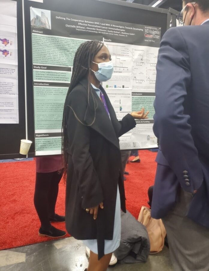 A person in black coat with a surgical mask standing in front of a poster