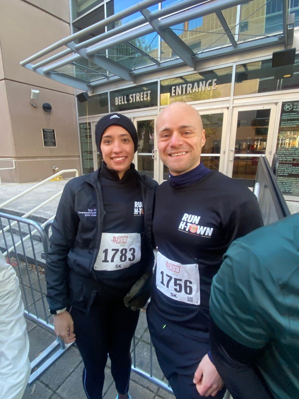Two people in black running gear with runner number bibs on for a 5k run