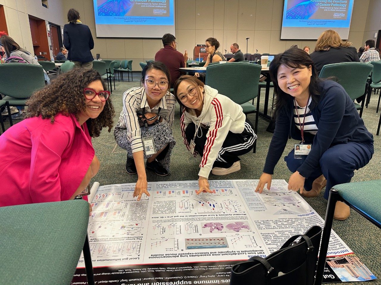 Four people grouped squatting around a poster that is laid out on the floor