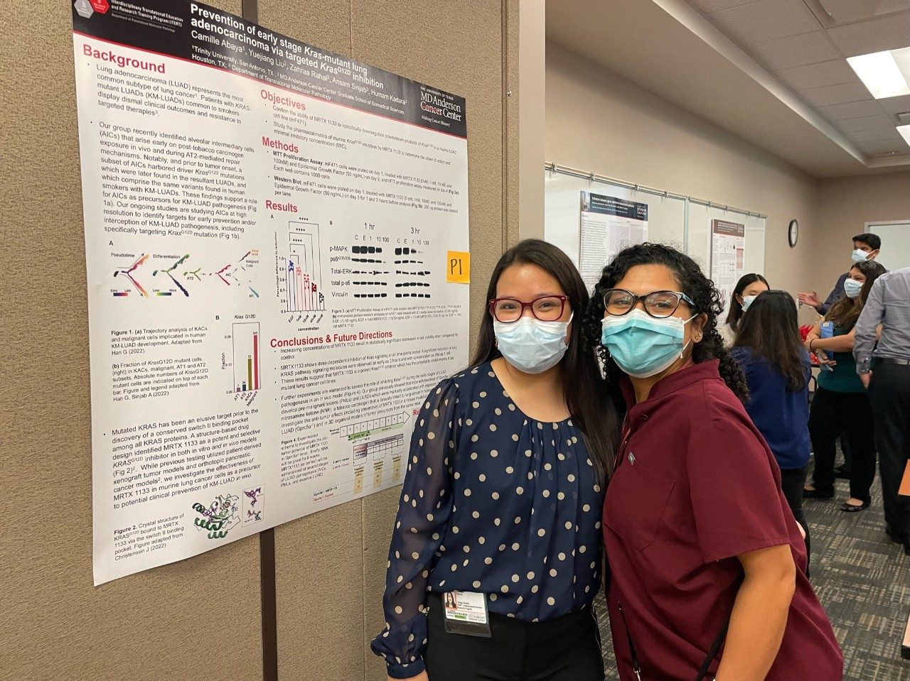 Two lab members standing next to a poster with masks on