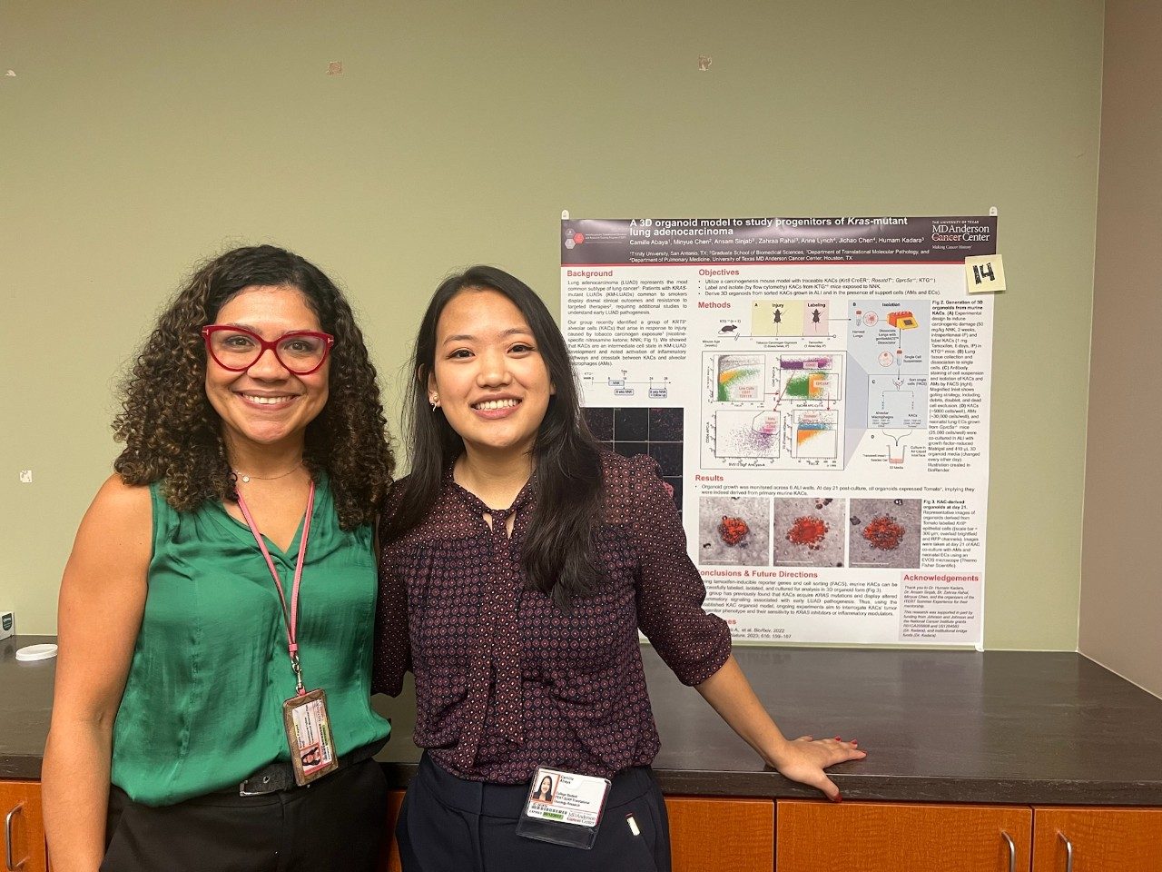 Two lab members standing next to a poster